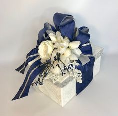 a white and blue flower arrangement in a gift box