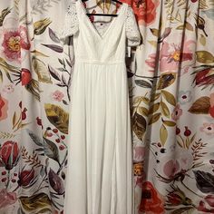 a white dress hanging on a floral curtain