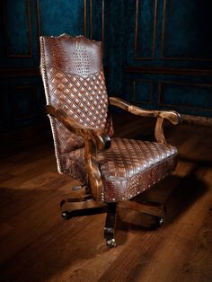 a leather office chair sitting on top of a wooden floor next to a blue wall