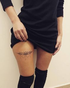 a woman's thigh with tattoos on her legs and knee high socks, standing against a wall