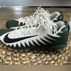 a pair of green and white shoes on top of a woven place mat with wood flooring