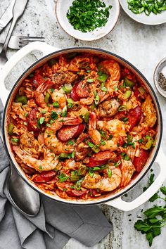 a skillet filled with shrimp and rice on top of a table next to silverware