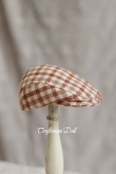 a small white and red hat sitting on top of a wooden stand next to a gray wall