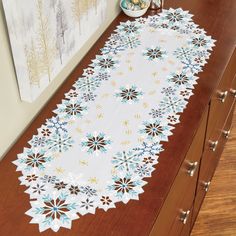 a white table runner with blue and yellow flowers on it sitting on a wooden counter