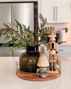 a wooden nutcracker is sitting next to a vase with greenery in it