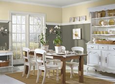 a dining room with green walls and white furniture