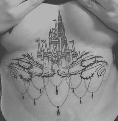 a woman's stomach with a castle tattoo on her belly and hands in the air