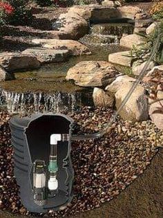 a water feature in a garden with rocks and gravel surrounding it, surrounded by flowers