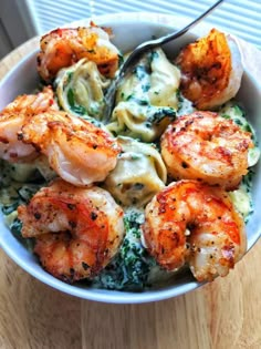 a bowl filled with pasta and shrimp on top of a wooden table