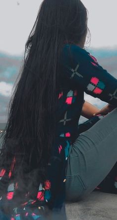 a woman with long hair sitting on the ground