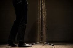 a person standing in front of a light with sand coming out of it's legs