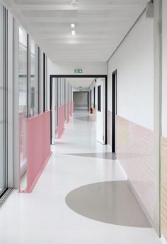 an empty hallway with pink dividers and white walls, along with large windows on both sides