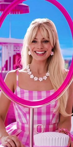 a woman sitting at a table with a cake in front of her and a pink ring around her neck