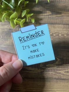 a hand holding a sticky note with reminder written on it