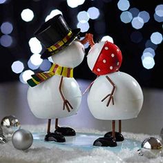 two snowmen with hats and scarves on their heads are standing next to each other