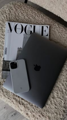 an apple laptop computer sitting on top of a rug next to a magazine with the cover open