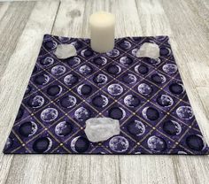 a candle is sitting on top of a purple and white table cloth with moon designs