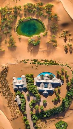 an aerial view of a house in the middle of sand dunes with trees around it