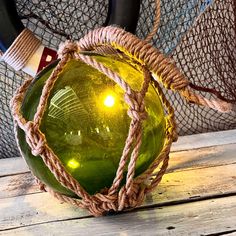 a green glass ball sitting on top of a wooden table next to some ropes and other items