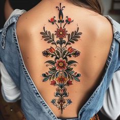 the back of a woman's neck with an intricate tattoo design on her lower back