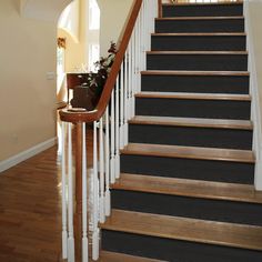 the stairs are painted black and white with wood treads on each handrail, along with a planter filled with flowers