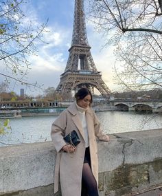 a woman leaning against a wall in front of the eiffel tower, paris