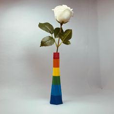 a single white rose in a multi - colored vase