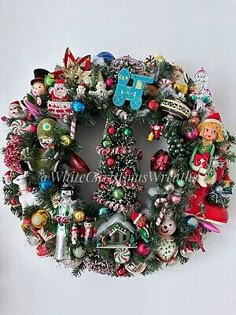 a christmas wreath hanging on the wall with ornaments and decorations around it's edges