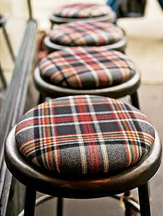 four plaid stools lined up on a bench