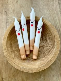 three candles with reindeer faces on them sitting in a bowl