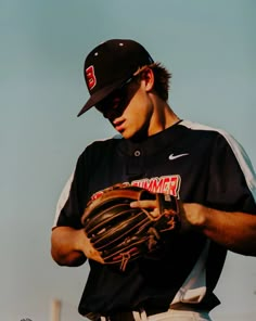 a baseball player holding a catchers mitt on top of his chest and looking down