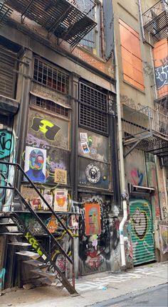 an alleyway with graffiti on the walls and stairs leading up to some buildings that have balconies above them