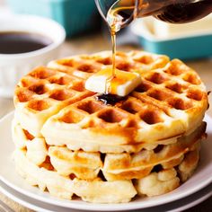 a stack of waffles with syrup being drizzled over them on a plate