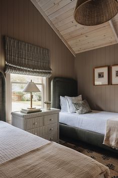 two twin beds in a bedroom with wood paneling on the walls and ceiling, next to each other