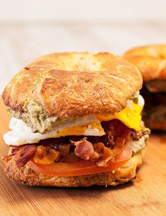 a close up of a sandwich with bacon and eggs on it sitting on a table