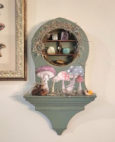 there is a clock with mushrooms on it and other items in the background, along with a framed painting