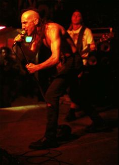 a shirtless man holding a microphone on stage