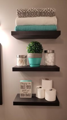 bathroom shelves with towels, toilet paper and a potted plant