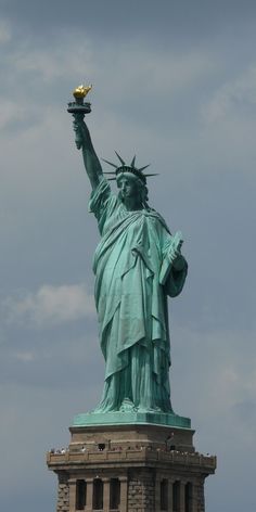 the statue of liberty is shown against a cloudy sky