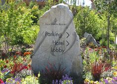 a large rock sitting in the middle of a garden filled with lots of flowers and plants