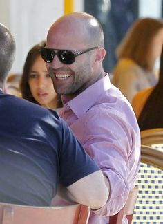 a man sitting at a table in front of another man with sunglasses on his head