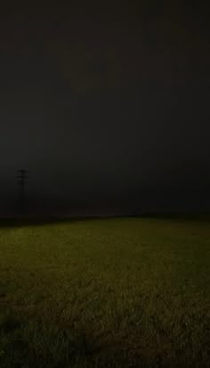 an empty field at night with power lines in the distance