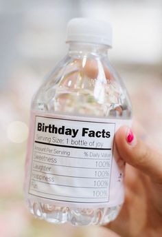 a person holding up a bottle of birthday fact