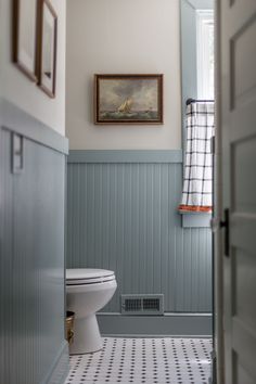 a white toilet sitting in a bathroom next to a painting on the wall above it