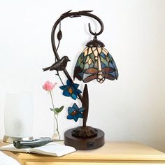 a lamp that is sitting on top of a table next to a book and flowers