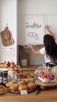 a woman standing in front of a counter filled with pastries and desserts on plates