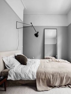 a bedroom with a bed, mirror and lamp on the wall next to each other