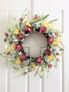 a floral wreath hanging on the front door with an arrow pointing to it's left side