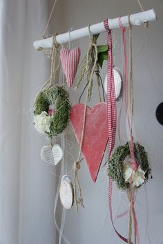 several hearts hanging from a wall with ribbons and flowers on the strings attached to them