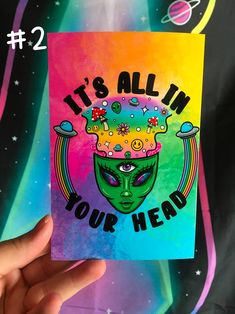 a hand holding up a card with an alien face on it that says, it's all in your head